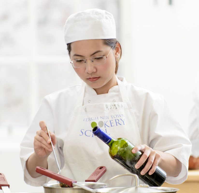 adding wine to the dish whilst learning how to cook Edinburgh